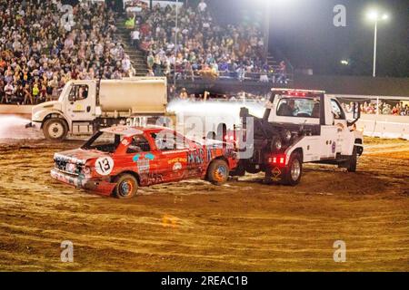 Costa Mesa, Kalifornien, USA. 11. Aug. 2018. Während ein Wasserwagen die Arena hinunterspritzt, räumt ein Abschleppwagen die zerstörten Autos in einem Demo-Derby in Costa Mesa, Kalifornien, aus. (Kreditbild: © Spencer Grant/ZUMA Press Wire) NUR REDAKTIONELLE VERWENDUNG! Nicht für den kommerziellen GEBRAUCH! Stockfoto