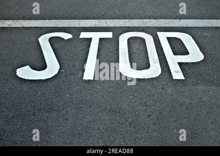 WORTSTOPP in weißen Buchstaben auf schwarzem Asphalthintergrund. Stockfoto