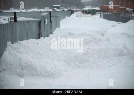 Schnee am Zaun. Große Schneeverwehungen. Schneebedeckte Passage. Industriegebiet im Winter. Stockfoto