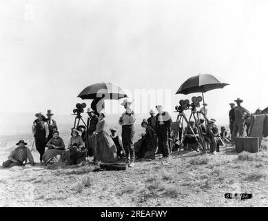 ALAN HALE (3. von links) Regisseur JAMES CRUZE (in karierter Jacke neben der linken Kamera) TULLY MARSHALL (vor 2 Kameras auf der rechten Seite) und andere Besetzungsmitglieder und Filmcrew (einschließlich Violinist für Stimmungsmusik) Am Drehort Candid in Utah im Jahr 1922 während der Dreharbeiten für DEN COVERED WAGON 1923 Regisseur JAMES CRUZE Roman Emerson Hough Kostümdesign Howard Greer Produzent Jesse L. Lasky Paramount Pictures Stockfoto