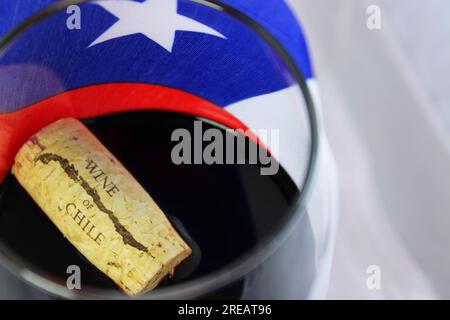 Becher mit Kork, schwimmend in chilenischem Rotwein und Hintergrundflagge Stockfoto