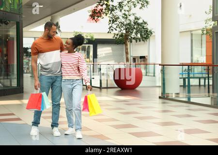 Familieneinkäufe. Glückliches Paar mit bunten Taschen im Einkaufszentrum Stockfoto