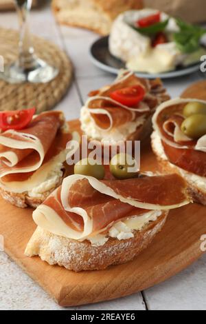 Leckere Sandwiches mit geräuchertem Schinken, Tomaten und Oliven auf dem Tisch, Nahaufnahme Stockfoto