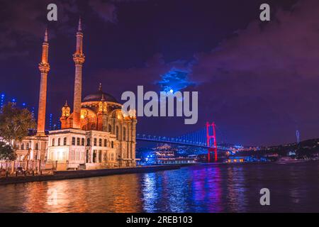 Ortaköy Moschee und Bosporus Brücke während der blauen Stunde, Vollmond und blauen Nachthimmel. Einer der beliebtesten Orte am Bosporus, Istanbul. Stockfoto