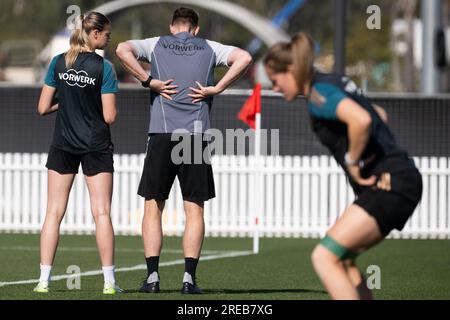 Tuggerah, Australien. 27. Juli 2023. Fußball: Weltmeisterschaft, Frauen, Training Deutschland: Jule Brand (l-r), Jan-Ingwer Callsen-Bracker, verantwortlich für das neuroathletische Training mit der deutschen Frauennationalmannschaft, und im Vordergrund trainiert Sydney Lohmann am Rande des Trainingsplatzes. Kredit: Sebastian Christoph Gollnow/dpa/Alamy Live News Stockfoto