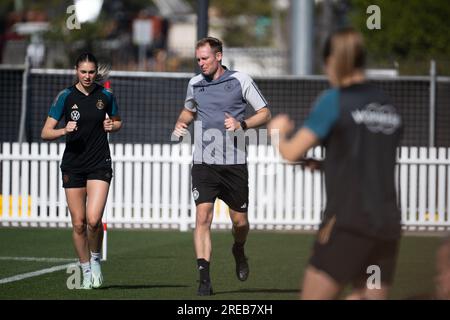 Tuggerah, Australien. 27. Juli 2023. Fußball: Weltmeisterschaft, Frauen, Training Deutschland: Jule Brand (l-r), Jan-Ingwer Callsen-Bracker, verantwortlich für das neuroathletische Training mit der deutschen Frauennationalmannschaft, und im Vordergrund trainiert Sydney Lohmann am Rande des Trainingsplatzes. Kredit: Sebastian Christoph Gollnow/dpa/Alamy Live News Stockfoto