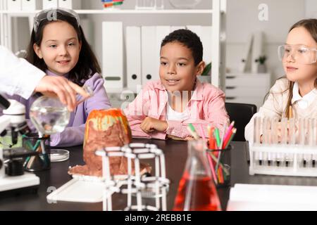 Kleine Kinder experimentieren mit Lehrer und chemischem Vulkan im Wissenschaftsunterricht Stockfoto