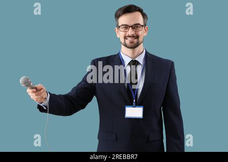 Männlicher Journalist mit Mikrofon auf blauem Hintergrund Stockfoto