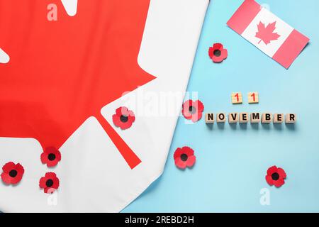 Mohnblumen mit kanadischer Flagge und Text 11. NOVEMBER auf blauem Hintergrund. Gedenktag Stockfoto