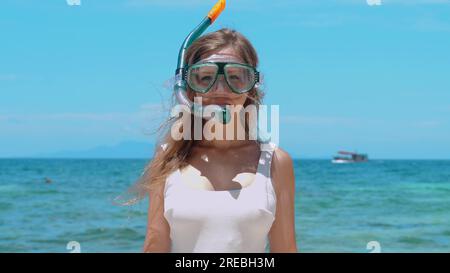 Eine Frau, die im türkisfarbenen Meer schnorchelt und die Maske abnimmt. Stockfoto