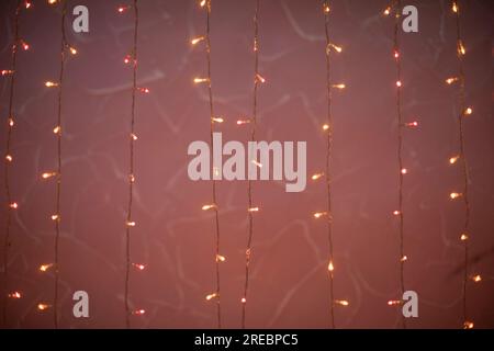 Rosa Girlanden. Glühbirnen auf Gewinde. Kleine Lichter im Dunkeln. Helle Dekoration. Stockfoto