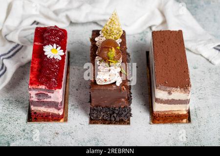 Verschiedene Kuchenscheiben. Tiramisu, Schokolade und Obstkuchen auf grauem Hintergrund Stockfoto