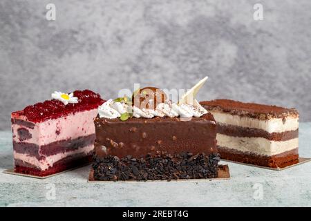 Verschiedene Kuchenscheiben. Tiramisu, Schokolade und Obstkuchen auf grauem Hintergrund Stockfoto