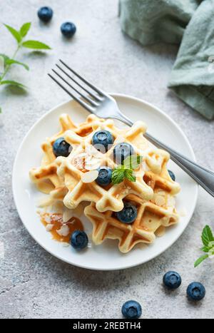 Frisch gebackene Waffeln mit frischen Blaubeeren auf Betongrau. Hausgemachtes Backen. Stockfoto