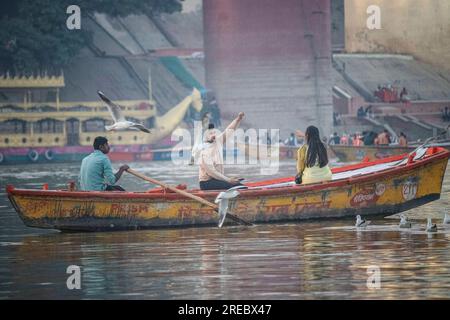 Ein paar machen eine Bootsfahrt auf dem Ganges River in Veranassi. Indien. Die Menschen bereiten in Varanasi am Ufer des Ganges, einer der ältesten bewohnten Städte der Welt und die heiligste der sieben heiligen Städte des Hinduismus, Scheiterhaufen vor. Jeden Tag werden in Manikarnika Ghat, dem größten und vielversprechendsten Einäscherungsghat, rund 100 Leichen auf Holzscheiterhaufen am Flussufer eingeäschert. Die ewige Flamme, die die Feuer nährt, soll seit Jahrhunderten brennen. Varanasi, Indien. Stockfoto