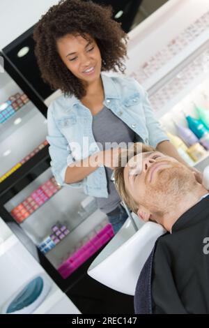 Weibliche Friseurin wäscht Männerhaare im Friseursalon Stockfoto