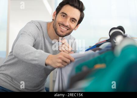 Ein hübscher junger Mann, der eine Jacke in seinem Schrank aussucht Stockfoto