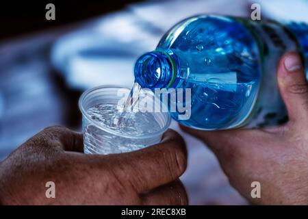 Reines Wasser wird aus einer Flasche Mineralwasser in ein klares Glas Gesundheit und Erfrischung gegossen Stockfoto