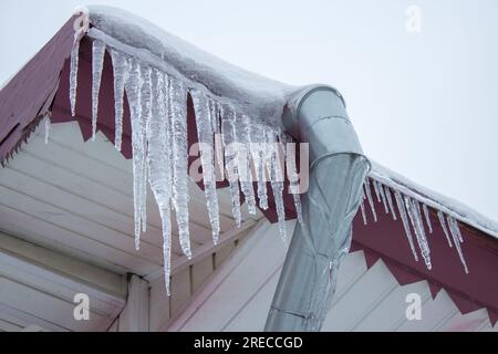 Gebäude mit großen Eiszapfen, Eiszapfen hängen vom Dach, vertikal, Eisstalaktiten hängen vom Dach Stockfoto