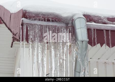 Eiszapfen an den Dächern der Gebäude. Schnee auf der Ablaufleitung Stockfoto