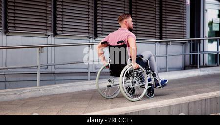 Mann Mit Körperlicher Behinderung Im Rollstuhl Auf Der Rampe Im Freien Stockfoto