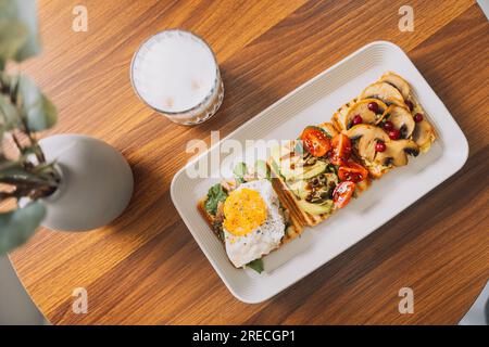 Zum Frühstück gibt es Toasts mit verschiedenen Belägen auf einem Teller mit einer Tasse Kaffee Stockfoto