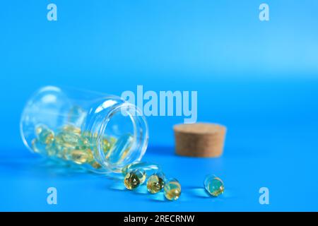 Omega 3 Kapseln in einer Glasflasche auf blauem Hintergrund. Gesundheitswesen, medizinische Pillen und Nahrungsergänzungsmittel. Gesundheitskonzept. Omega-3 ungesättigte Fettsäuren Stockfoto