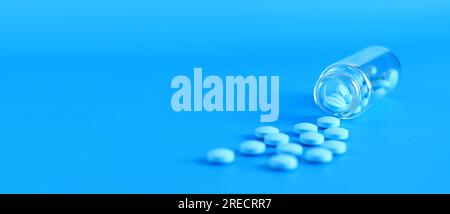 Blaue Pillen aus einer Glasflasche auf blauem Hintergrund. Vitamin-B-Komplex, Seitenansicht, Kopierraum. Gesundheitswesen, medizinische Pillen und Nahrungsergänzungsmittel Stockfoto