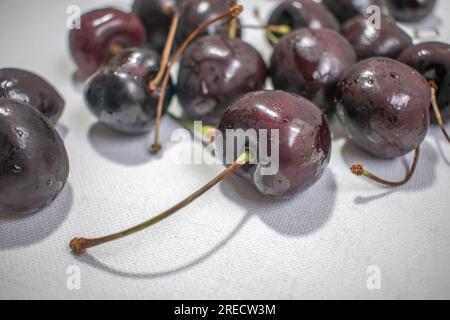 Black Cherry: Ein eindrucksvolles Bild mit einer dunklen schwarzen Kirsche auf einem strahlend weißen Hintergrund, das ein optisch ansprechendes und auffälliges Kont Stockfoto