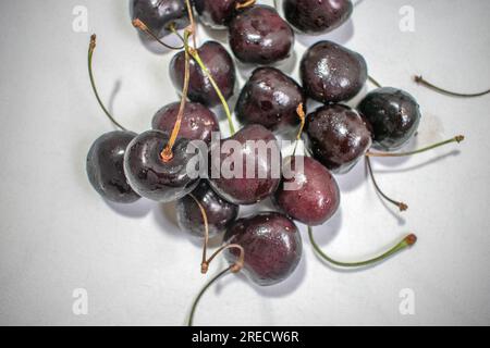 Black Cherry: Ein eindrucksvolles Bild mit einer dunklen schwarzen Kirsche auf einem strahlend weißen Hintergrund, das ein optisch ansprechendes und auffälliges Kont Stockfoto