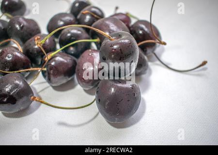 Black Cherry: Ein eindrucksvolles Bild mit einer dunklen schwarzen Kirsche auf einem strahlend weißen Hintergrund, das ein optisch ansprechendes und auffälliges Kont Stockfoto