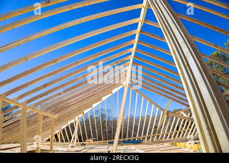 Auf der Neubaustelle des Hauses werden Holzrahmendächer mit Stützbalken für das Dach gebaut. Stockfoto
