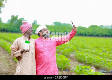Indische Landwirtschaft. Zwei Bauern, die eine leere Flasche in den Händen halten, ein Bauer und ein Agronom Stockfoto