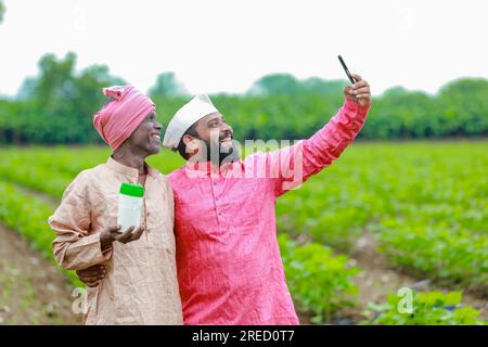 Indische Landwirtschaft. Zwei Bauern, die eine leere Flasche in den Händen halten, ein Bauer und ein Agronom Stockfoto