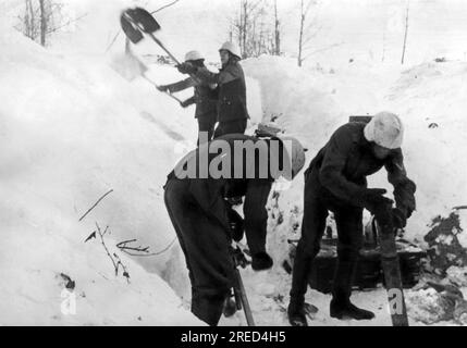 Deutsche Soldaten schaufeln Schnee aus dem Graben, während ein Granatwerfer auf der rechten Seite vorbereitet ist. [Maschinelle Übersetzung] Stockfoto