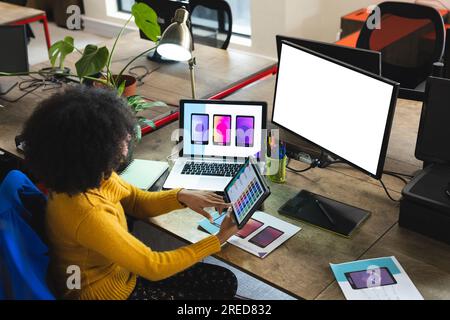 afroamerikanische Designerin, die Tablet und Computer nutzt, mit Kopierbereich am Schreibtisch im Büro Stockfoto