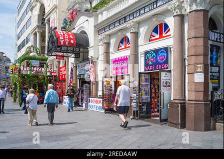 Die Leute, die an einem sonnigen Sommertag auf dem Leicester Square spazieren gehen, kommen an den bunten Geschäften vorbei, die an das IMAX-Kino und das Empire Casino angrenzen. London, England, Großbritannien Stockfoto