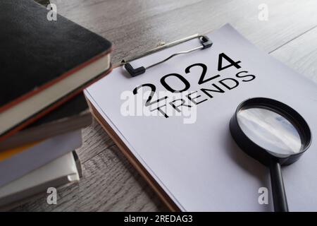 Vergrößerungsglas und Text 2024-TRENDS in der Zwischenablage. Stockfoto