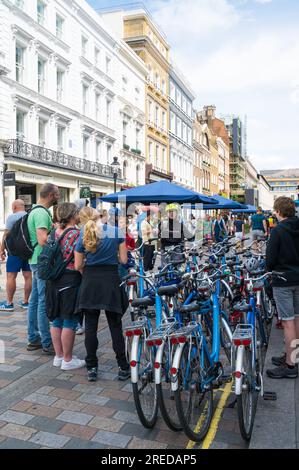 Junge weibliche Reiseleiterin, die eine Gruppe von Radtouristen anspricht. Covent Garden, London, England, Großbritannien Stockfoto