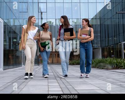 Eine Gruppe verschiedener Studentinnen im Teenageralter, die auf dem Campus spazieren und plaudern Stockfoto