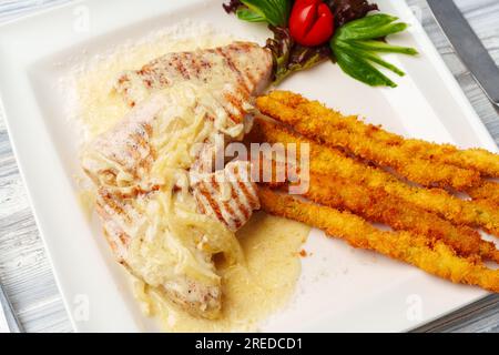 Hähnchen in Sauce und gebratene Kartoffelstangen auf Teller Stockfoto