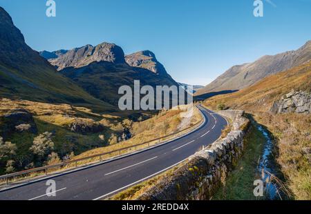 A82 Straße durch Glen Coe unterhalb von Bidean nam Bian und der Eingang zum Coire Gabhail mit den Hügeln von Gearr Aonach und Aonach Dubh dahinter. Stockfoto