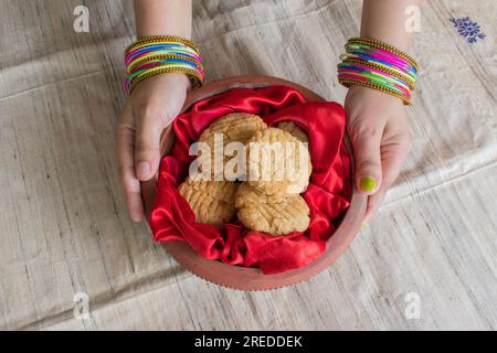 Thekua, ein indisches süßes Gericht oder Snacks in Erdtöpfen, die von einer Frau gehalten werden. Beliebt in bihar jharkhand. Prashad in Chathparv oder Puja oder Festival Stockfoto