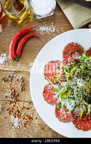Rindercarpaccio. Borettanzwiebeln, sonnengetrocknete Tomaten, Trüffeldressing, Rucola-Salat, Parmesan-Käse. Italienische traditionelle Antipasti-Snacks für l Stockfoto