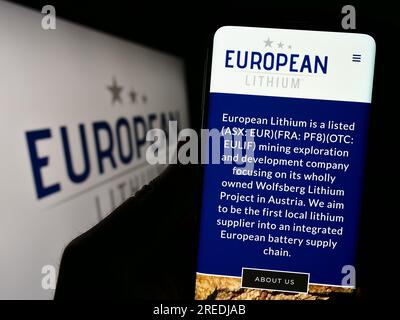 Person, die ein Mobiltelefon mit dem Logo des Bergbauunternehmens European Lithium Limited auf dem Bildschirm vor der Unternehmenswebseite hält. Konzentrieren Sie sich auf das Display des Telefons. Stockfoto
