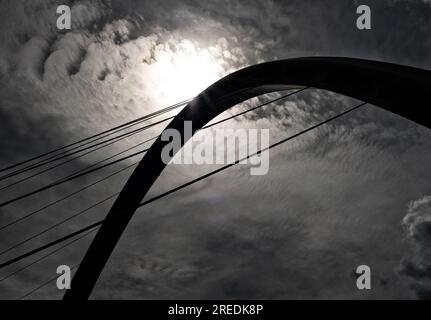 Die Silhouette des Bogens der Gateshead Millenium Bridge in Newcastle, England, eingerahmt vor einem bewölkten Himmel. Stockfoto