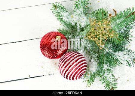 Schmuck zu Weihnachten oder Neujahr. Tannenzweigen und helle Dekorationen auf einer weißen Holzoberfläche. Stockfoto