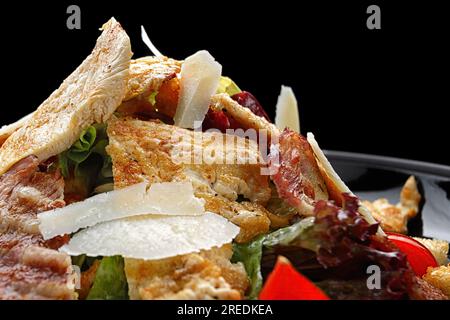 Köstlicher Caesar Salat garniert mit knusprigem Speck, gegrilltem Hähnchen und Parmesan Käse Stockfoto