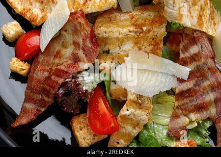 Köstlicher Caesar Salat garniert mit knusprigem Speck, gegrilltem Hähnchen und Parmesan Käse Stockfoto