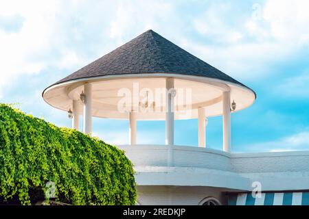 Der obere Teil der gefliesten Pavillon-Rotunde. Wunderschöne Kuppel aus Beton. Zeiger auf die Hauptpunkte auf dem Dach. Bautechnik mit moderner Technik Stockfoto